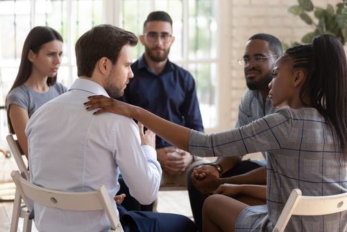 Professional woman consoling man in a circle group